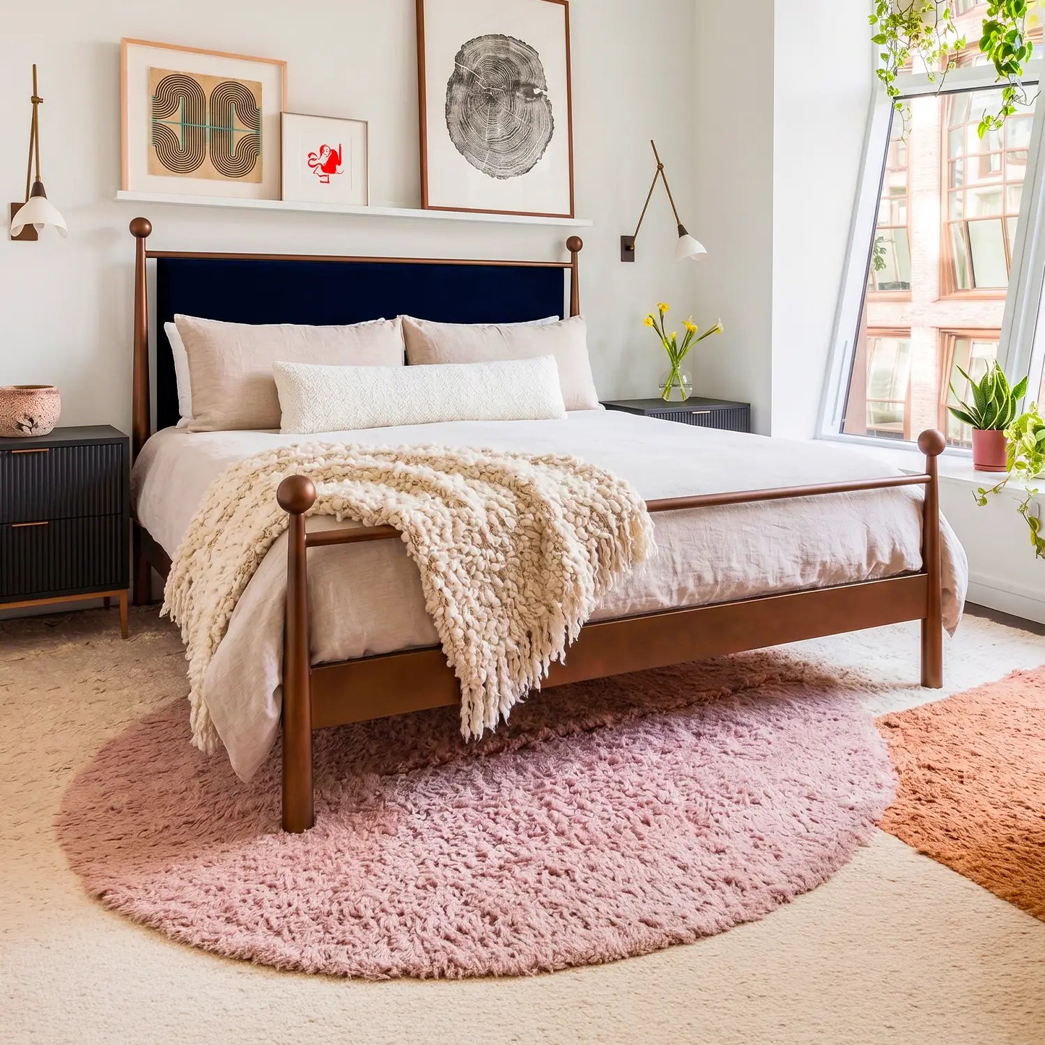 Olympus Iron Bed shown in Opaque Copper Finish with Black Velvet Performance Fabric. The Olympus bed is shown in a clean natural aesthetic with white walls, houseplants, and layered shaggy rugs in beige, pink, and coral.